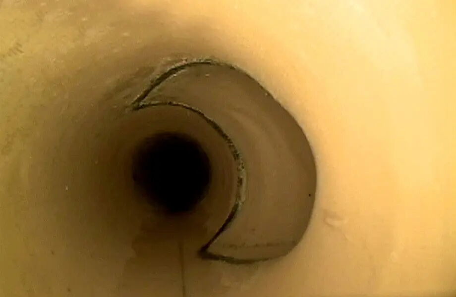 Blick durch ein hellbraunes Rohr mit glatten Wänden, leicht schräg. Im Inneren ist es dunkel, der Blick endet in einer schwarzen Öffnung.